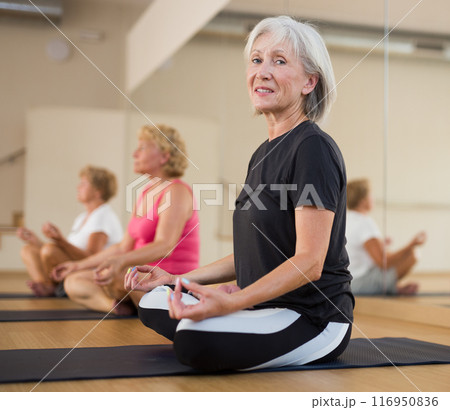 Group of mature women meditates in the half-lotus position 116950836