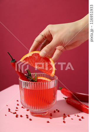 Grapefruit cocktail, pepper and grapefruit slice in hand on pink background, close up Grapefruit cocktail, pepper and grapefruit slice in hand on pink background, close up 116951933