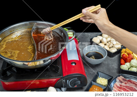 A hand holding chopsticks with a piece of meat on it A hand holding chopsticks with a piece of meat on it 116953212