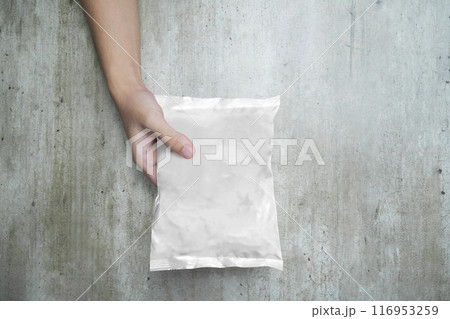 A person is holding a bag of instant noodle that is wrapped in foil A person is holding a bag of instant noodle that is wrapped in foil 116953259