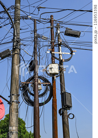 A bunch of power lines are tangled together and the sky is blue 116953398
