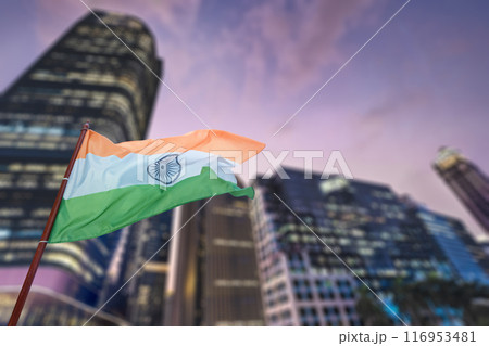 A large green, white and red Indian flag is flying in the air above a city 116953481