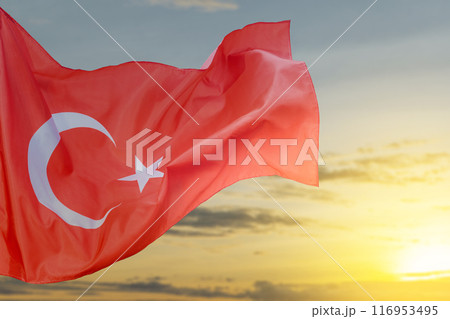 A Turkey flag with a star and crescent moon flying in the sky A Turkey flag with a star and crescent moon flying in the sky 116953495