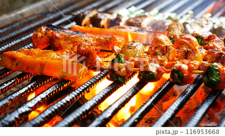 BBQ Barbecue grilled meat stick on fire flame with hot charcoal cooking outside. Beef grilling picnic outdoor with smoke bacon spicy sausage for party. Grill pork bbq on fire flame BBQ Barbecue grilled meat stick on fire flame with hot charcoal cooking outside. Beef grilling picnic outdoor with smoke bacon spicy sausage for party. Grill pork bbq on fire flame 116953668