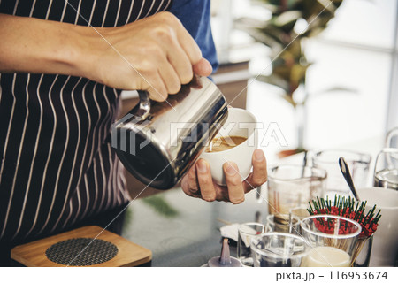 Coffee barista pour espresso shot and make latte art hot coffee cup. Cappuccino with milk in italian coffee shop cafe. Close up hands of barista make brown latte art for customer cafeteria. Coffee barista pour espresso shot and make latte art hot coffee cup. Cappuccino with milk in italian coffee shop cafe. Close up hands of barista make brown latte art for customer cafeteria. 116953674