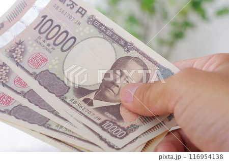 10万円のお金を手に持つ男性 116954138