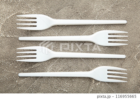 Many plastic forks on a grey concrete background. Many plastic forks on a grey concrete background. 116955665