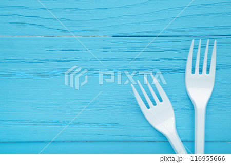 Two white plastic forks on a blue wooden background. Two white plastic forks on a blue wooden background. 116955666