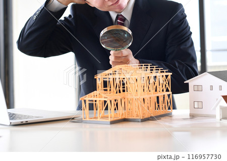 虫眼鏡で建築模型を覗くスーツ姿の悩む男性 116957730