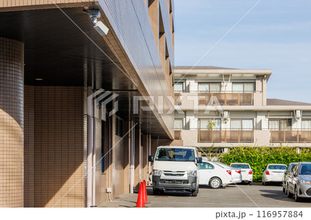 社屋の玄関に設置された駐車場を監視する防犯カメラ 116957884