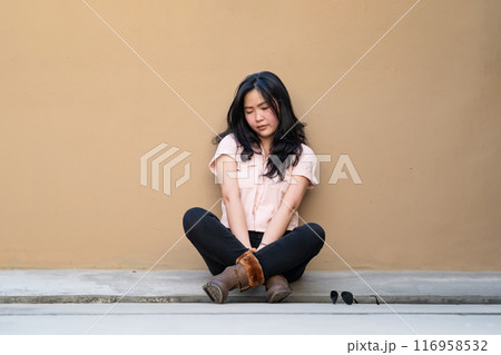 Asian woman is sitting alone on the rooftop of building with tried and disappointed mood and tone in that day. 116958532