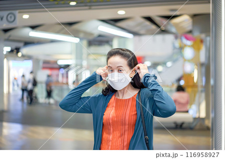 Asian Woman was wearing and putting white face mask on her face in shopping mall. 116958927