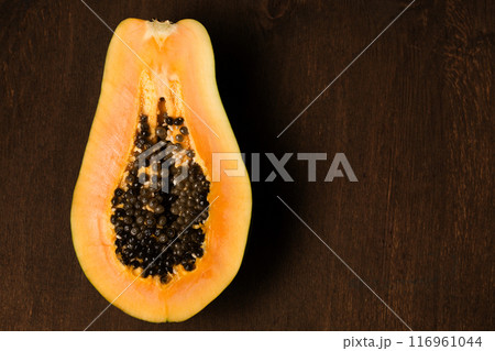 Half of a juicy ripe papaya on a brown background 116961044