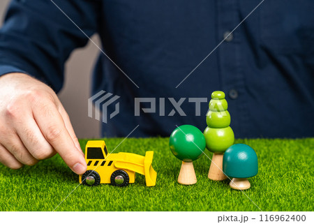 A man with a bulldozer is going to cut down trees in a forest. Clearing land for construction. Illegal logging. Protect the environment, stop deforestation. 116962400