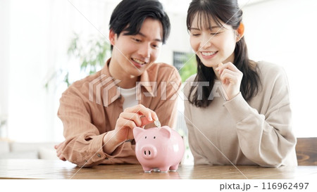 貯金箱にお金を入れるカップル 116962497