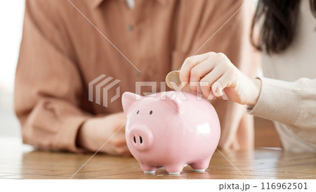 貯金箱にお金を入れるカップル 116962501