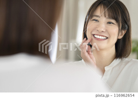 鏡を見て微笑むきれいな歯並びの女性 116962654