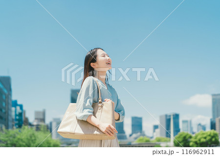 青空とビル群を背景にしたビジネスウーマン 116962911