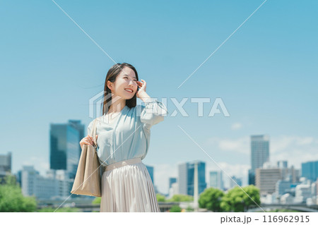 青空とビル群を背景にしたビジネスウーマン 青空とビル群を背景にしたビジネスウーマン 116962915