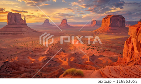 A vast desert with towering red rocks basks in a sunsets golden hues, creating a warm, ethereal glow. 116963055