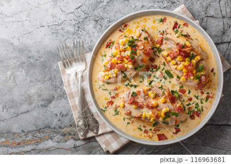 Pan-seared chicken in a creamy, spicy, street corn sauce with bacon closeup on the plate. Horizontal top view 116963681