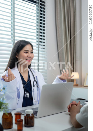 Friendly Female Doctor Consulting with Patient in Modern Medical Office, Smiling and Engaging in Conversation 116963780