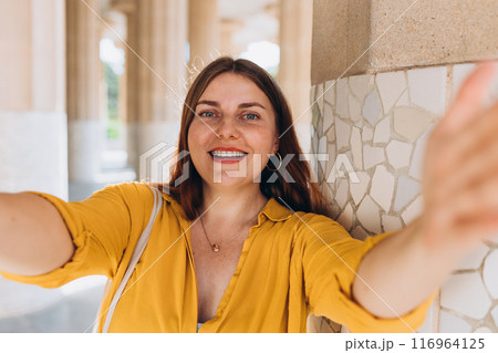 Beautiful female in Gaudi garden, Spain, Barcelona. Young traveling woman taking selfie outdoors. Concept of travel, tourism and vacation in city. Hypostyle hall Beautiful female in Gaudi garden, Spain, Barcelona. Young traveling woman taking selfie outdoors. Concept of travel, tourism and vacation in city. Hypostyle hall 116964125