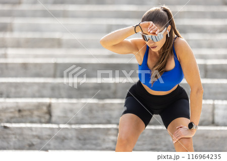A tired young female runner rests after an exhausting run up the stairs 116964235