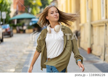 Rear view portrait of happy carefree Caucasian woman looking at side walking on urban city street 116966226