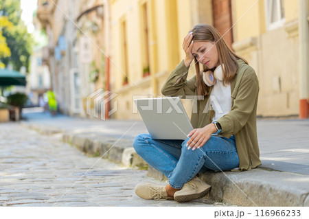 Displeased young woman using laptop working, loses becoming surprised sudden lottery result outdoors 116966233