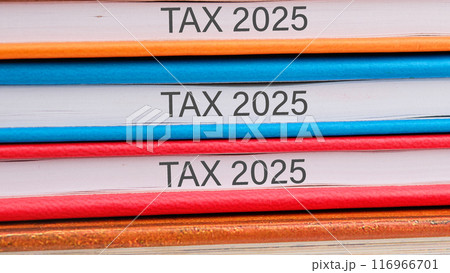 Conceptual tax 2025 symbol. Copy space. Tax 2025 words written close-up on the ends of the notebooks Conceptual tax 2025 symbol. Copy space. Tax 2025 words written close-up on the ends of the notebooks 116966701