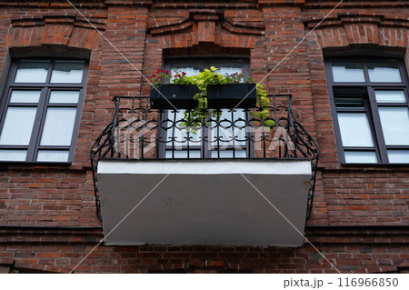 A balcony facing the street from an old brick house A balcony facing the street from an old brick house 116966850