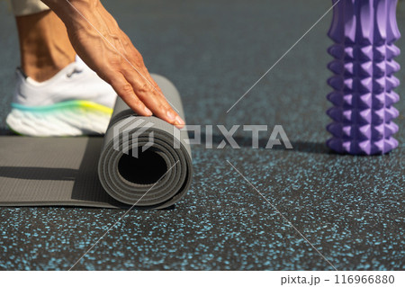 Man hands unrolling yoga mat before practice at sports ground. Outdoor. Copy space. Yoga, sport, healthy lifestyle concept. Close up. 116966880