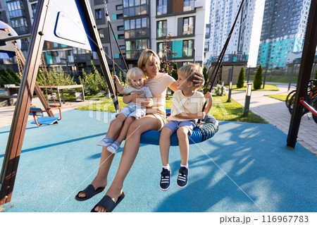 Mother Enjoys Quality Time With Her Two Sons on the Playground in a Sunny Urban Park Mother Enjoys Quality Time With Her Two Sons on the Playground in a Sunny Urban Park 116967783