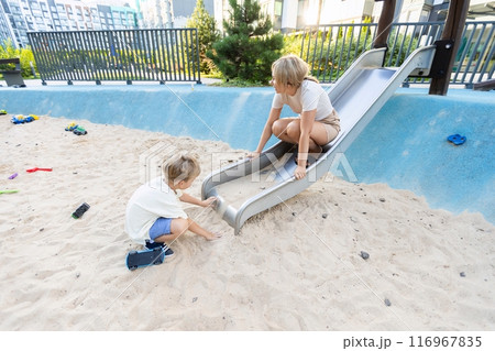 Mother And Her Two Sons Enjoying Time Together At The Playground Slide In Bright Sunshine Mother And Her Two Sons Enjoying Time Together At The Playground Slide In Bright Sunshine 116967835