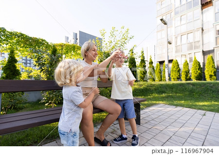 Mother Enjoys Playtime With Two Sons at Playground During Sunny Afternoon Mother Enjoys Playtime With Two Sons at Playground During Sunny Afternoon 116967904