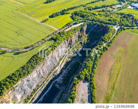 An aerial view captures the scenic beauty of the deserted Velka Amerika limestone quarry in Czechia, surrounded by lush greenery and farmland. An aerial view captures the scenic beauty of the deserted Velka Amerika limestone quarry in Czechia, surrounded by lush greenery and farmland. 116968696