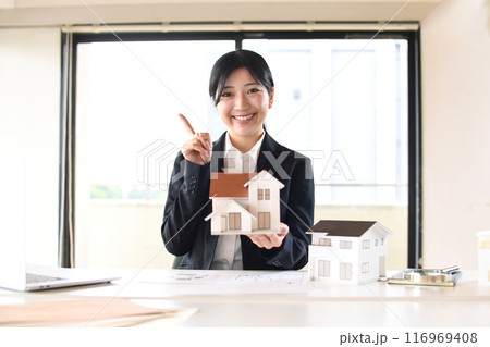 住宅模型を持ち人差し指を振るう女性会社員 住宅模型を持ち人差し指を振るう女性会社員 116969408