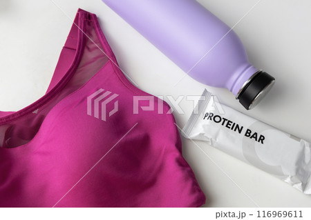 Concept of sports lifestyle. Flat lay sports top bra, drinking bottle for water and protein diet bar 116969611