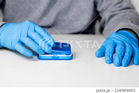 Man in surgical groves with pill organizer. Man in surgical groves with pill organizer. 116969802
