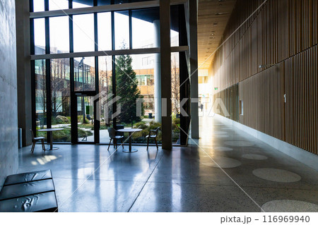 Hall in a modern building with large glass windows and a sitting area. 116969940