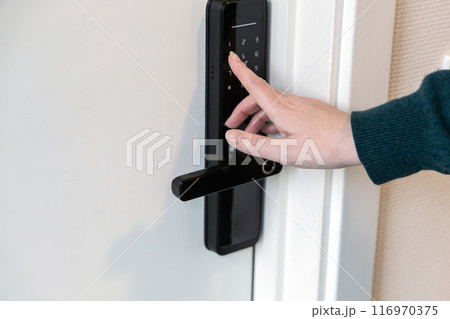 A human hand presses buttons with numbers to enter a code to open the door. A human hand presses buttons with numbers to enter a code to open the door. 116970375