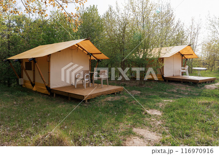 Cozy open glamping tents with light inside in summer camp. Camping tent for holiday and vacation Cozy open glamping tents with light inside in summer camp. Camping tent for holiday and vacation 116970916