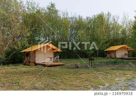 Cozy open glamping tents with light inside in summer camp. Camping tent for holiday and vacation 116970918