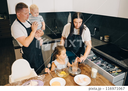 The Joy of Family Cooking Together in a Modern Kitchen Setting for Memorable Experiences. Happy family enjoys moments of cooking at home. 116971067