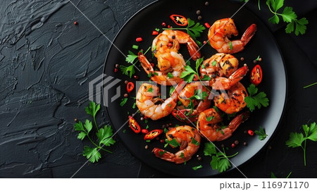 Grilled tiger prawns in white plate with spices on vintage black background, top view, copy space. Stone kitchen table with seafood dinner 116971170
