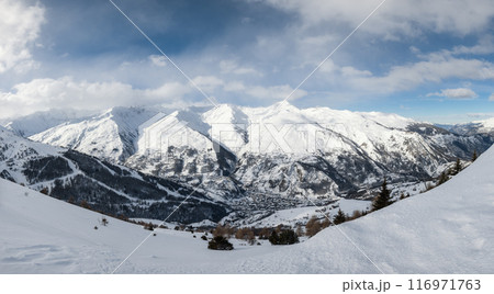 Small village nestled between enormous snowy mountains 116971763