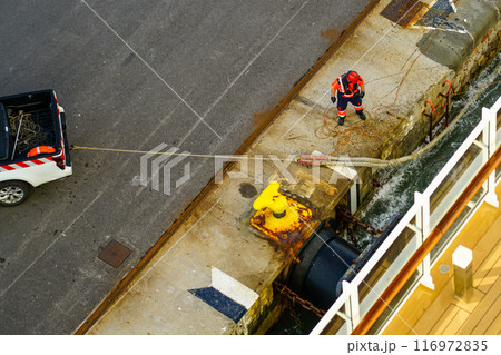 The process of mooring a large ship at the harbor pier, pulling the rope ashore using a pickup 116972835