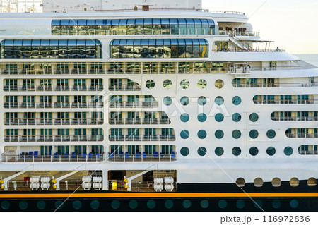 Large cruise ship side view fragment with round portholes rows and cabins balconies with railing Large cruise ship side view fragment with round portholes rows and cabins balconies with railing 116972836