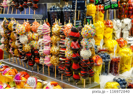 Chocolate coated fresh strawberry skewers at fruit stall at famous Barcelona food market La Boqueria Chocolate coated fresh strawberry skewers at fruit stall at famous Barcelona food market La Boqueria 116972840